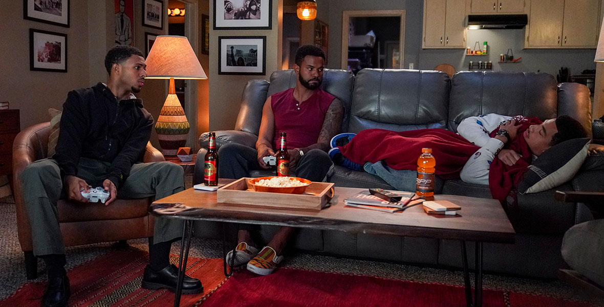 (Left to Right) Actors Diggy Simmons and Trevor Jackson sit in a chairs and holding video game controllers while actor Marcus Scribner lays horizontally on a couch.
