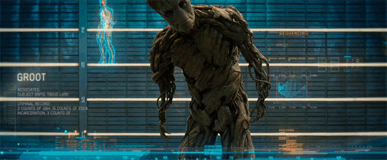 A gif of full-size adult Groot from Guardians of the Galaxy. Groot is being booked by the Nova Corp and they are analyzing him on a large high-tech screen. On the left it says his name and some additional information about him that is hardly discernable. Groot peers towards the camera and approaches slowly to get a closer look.