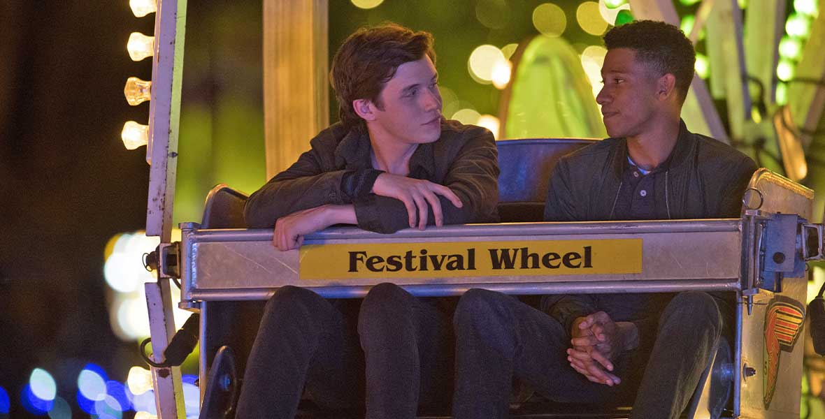 Actors Nick Robinson and Keiynan Lonsdale sit in a Ferris wheel at nighttime