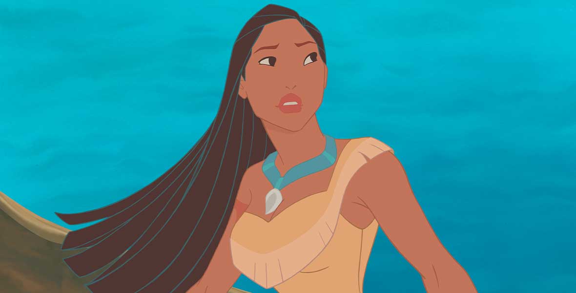 Pocahontas wears a tan, one-shouldered dress adorned with fringe. She wears a turquoise necklace with a white charm. She sits in a wood canoe and a bright blue river is seen behind her.