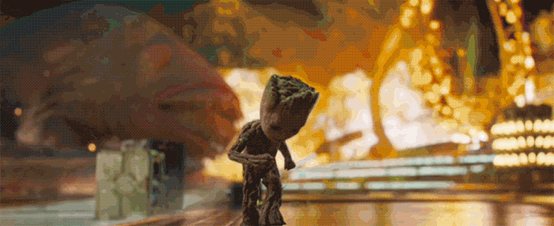 A gif of Baby Groot from Guardians of the Galaxy Vol.2. Groot is dancing by himself while a battle rages behind him. Large tentacles from a monster can be seen writhing around in the back left corner and a large hoop that is on fire crosses the scene. Baby Groot is paying no attention to the chaos and dances across the screen.