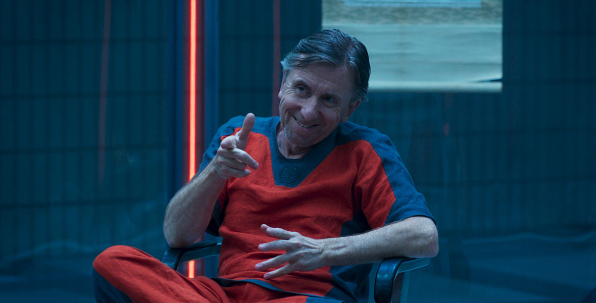 Actor Tim Roth as Emil Blonsky sits in a jail cell and wears a bright orange jumpsuit 