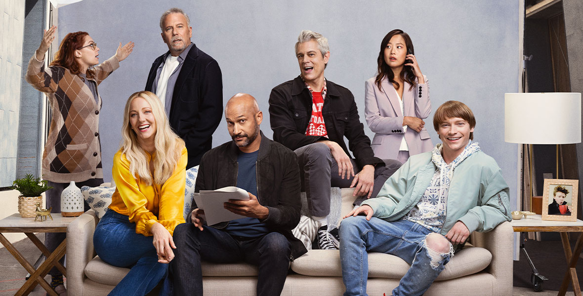 The promotional poster for Reboot features the following stars sitting or standing around a couch on a soundstage: (Left to Right) Rachel Bloom, Judy Greer, Paul Reiser, Keegan-Michael Key, Johnny Knoxville, Krista Marie Yu, and Calum Worthy. Rachel is throwing papers into the air as Keegan-Michael reviews his script. Krista Marie is taking a call on her cell phone. Above the cast is a boom mic, the Hollywood Hills, and a poster for Step Right Up.