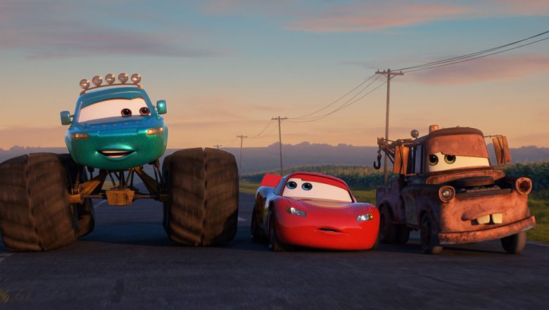 Lightning McQueen (center) and his best friend Mater (far right) from the beloved Cars franchise are joined by a new friend/Monster truck as they travel down a highway at dusk in the animated series Cars on the Road.