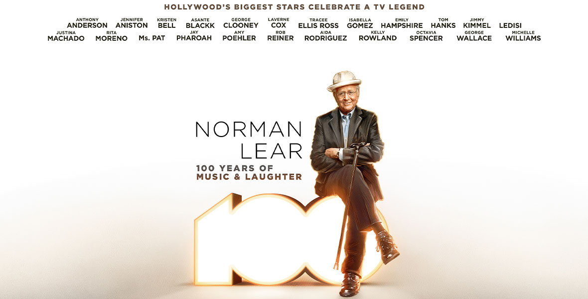 In a promotional image for ABC’s Norman Lear: 100 Years of Music and Laughter, Norman Lear is wearing a white hat, a dark sport coat and slacks, and his arms are crossed; his cane is hanging from one arm. He’s sitting on the number “100,” lit up from within. A listing of the stars appearing in the special is seen at the top of the image, and the ABC and Hulu logos are seen at the bottom.