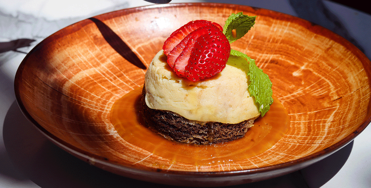 Chocolate cake with a flan custard baked top and caramel sauce, served on a brown plate.