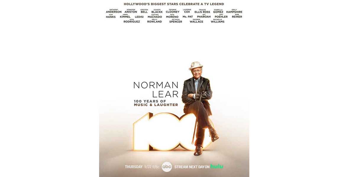 Norman Lear sits on a large 100 with his arms folded across his chest and legs crossed. He wears a gray suit and white hat. The text “Norman Lear: 100 Years of Music and Laughter” is next to him along with logos for ABC and Hulu below him.