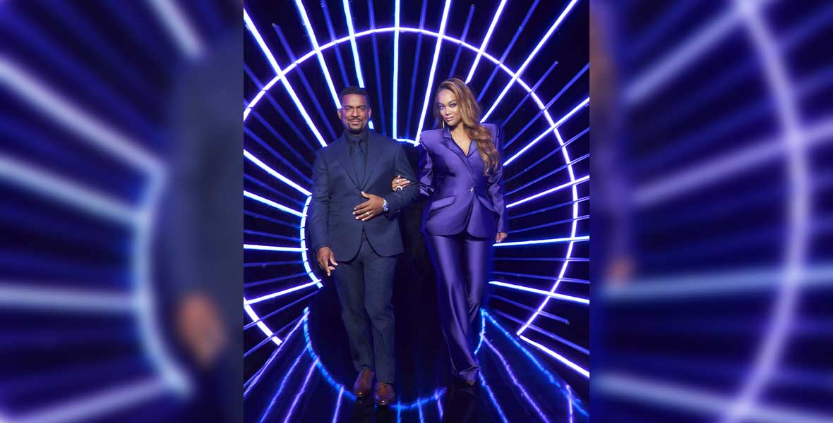 Supermodel and businesswoman Tyra Banks stands next to actor and television personality Alfonso Ribeiro. Behind them is a bold screen showing dark purple and dark blue lights shaped in a circle with lines radiating out.
