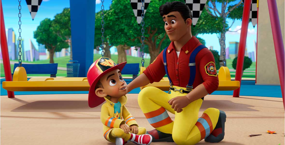 An animated young boy wears a red firefighter helmet and yellow coat. He is sitting next to an adult male character who has his hand on his shoulder. The man wears a red shirt and yellow firefighter pants. Behind them are lush green trees, checkered flags, and a swing set.