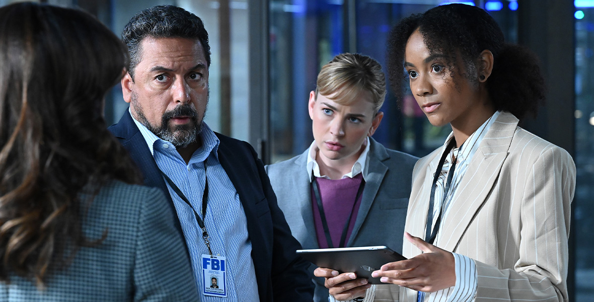 Actors Felix Solis, Britt Robertson, and Michelle Nuñez stand side by side while each wearing blazers and dress shirts. Each have lanyards around their necks holding their ID cards. Nunez holds a tablet in her hands.