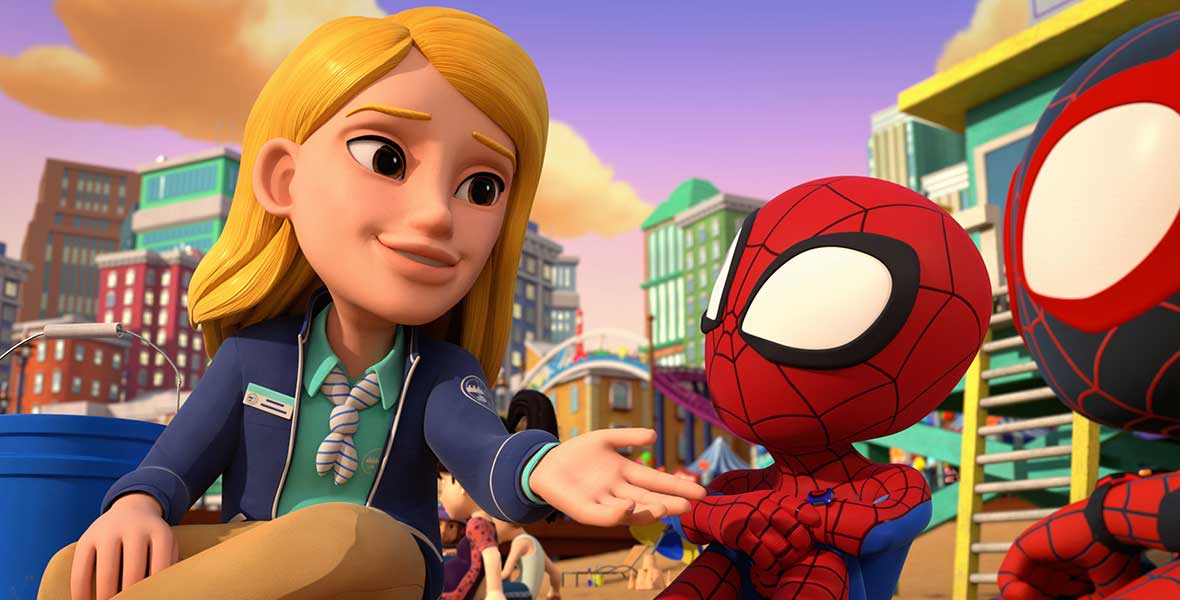 Animated character Isla Coralton sits on a bench next to Team Spidey. She wears a teal shirt, blue jacket, tan slacks, and a name tag. Behind them are metropolitan buildings and sand. The sky is a purple-blue color with a large fluffy cloud.