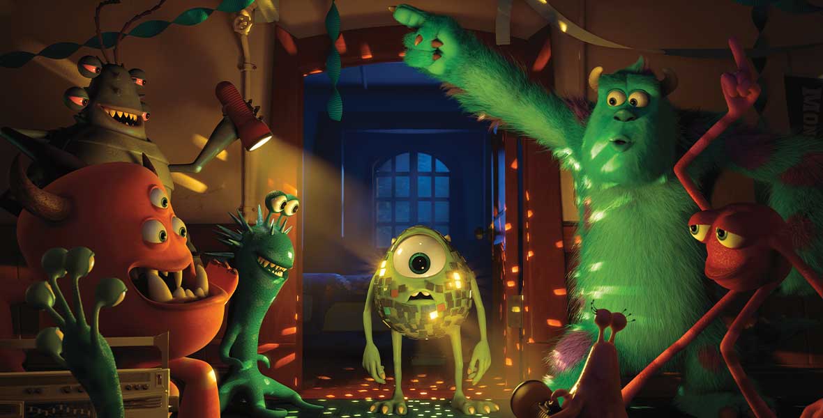 In a still from Monsters University, Mike Wazowski, voiced by Billy Crystal, is covered in reflective panels, making him look like a disco ball. Sulley, voiced by John Goodman, and other monsters are dancing and smiling around him.