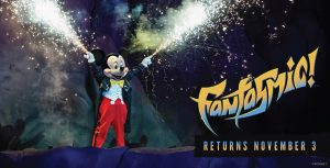 In a promo image for Fantasmic! returning to Disney’s Hollywood Studios at Walt Disney World Resort, Mickey Mouse is seen with sparks flying out of his fingertips. He’s wearing a sparkly black tailcoat, red pants, and a yellow bow tie. The logo for Fantasmic! is seen in the lower right of the image, and beneath it are the words “Returns November 3.”