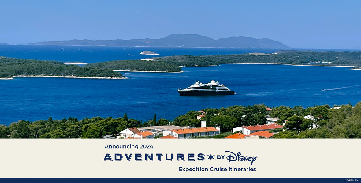 A promo image for Adventures By Disney’s new Adriatic Sea Expedition Cruise. A ship is seen in the middle of a clear blue sea, surrounded by several tree-covered islands, and some low mountains in the distance. In the foreground of the image are some homes with orange-tiled roofs. The sky is blue, with no clouds. At the bottom of the image are the words “Announcing 2024 Adventures By Disney Expedition Cruise Itineraries.”