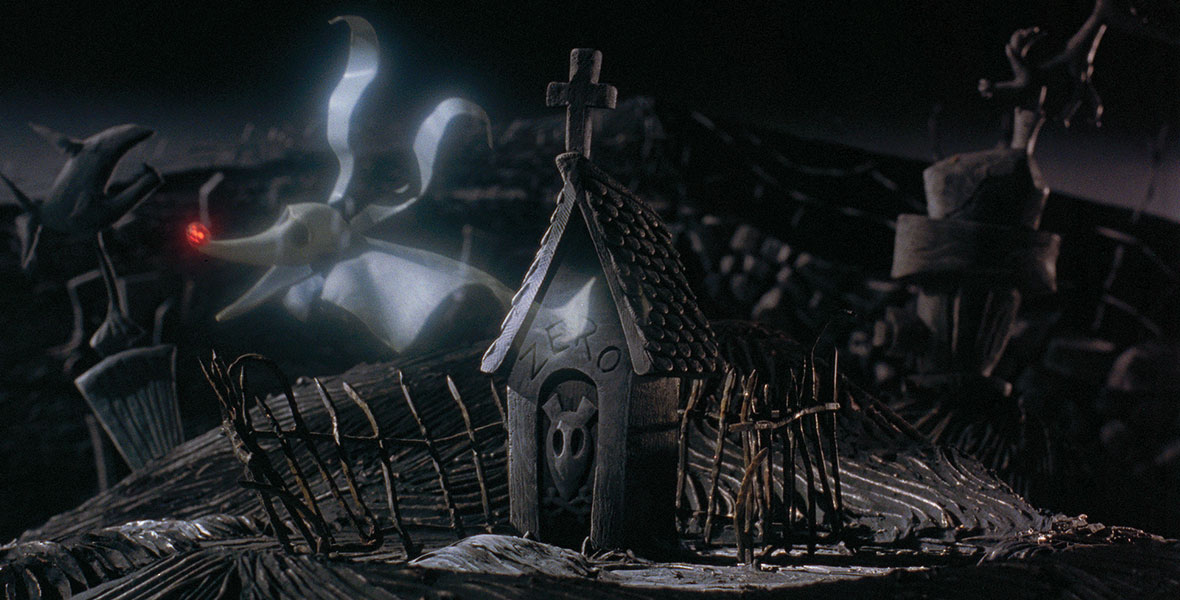 In a still from Tim Burton’s The Nightmare Before Christmas, Zero, a dog styled like a white “sheet ghost,” floats above his gravestone, which is stylized as a doghouse labelled with his name and a dog skull on the front door.