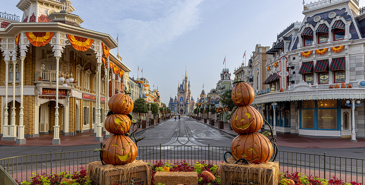 Two sets of three pumpkins are stacked on two bales of hay along Main Street, U.S.A. Cinderella Castle is the middle in the distance.