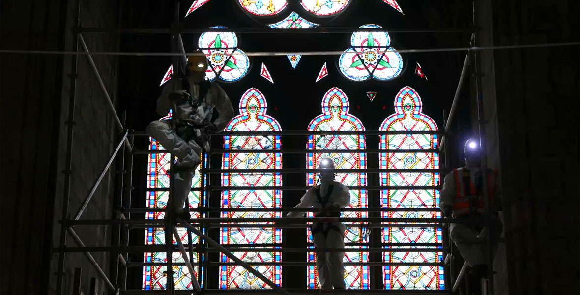 Construction works repair stained glass in the Notre Dame cathedral.