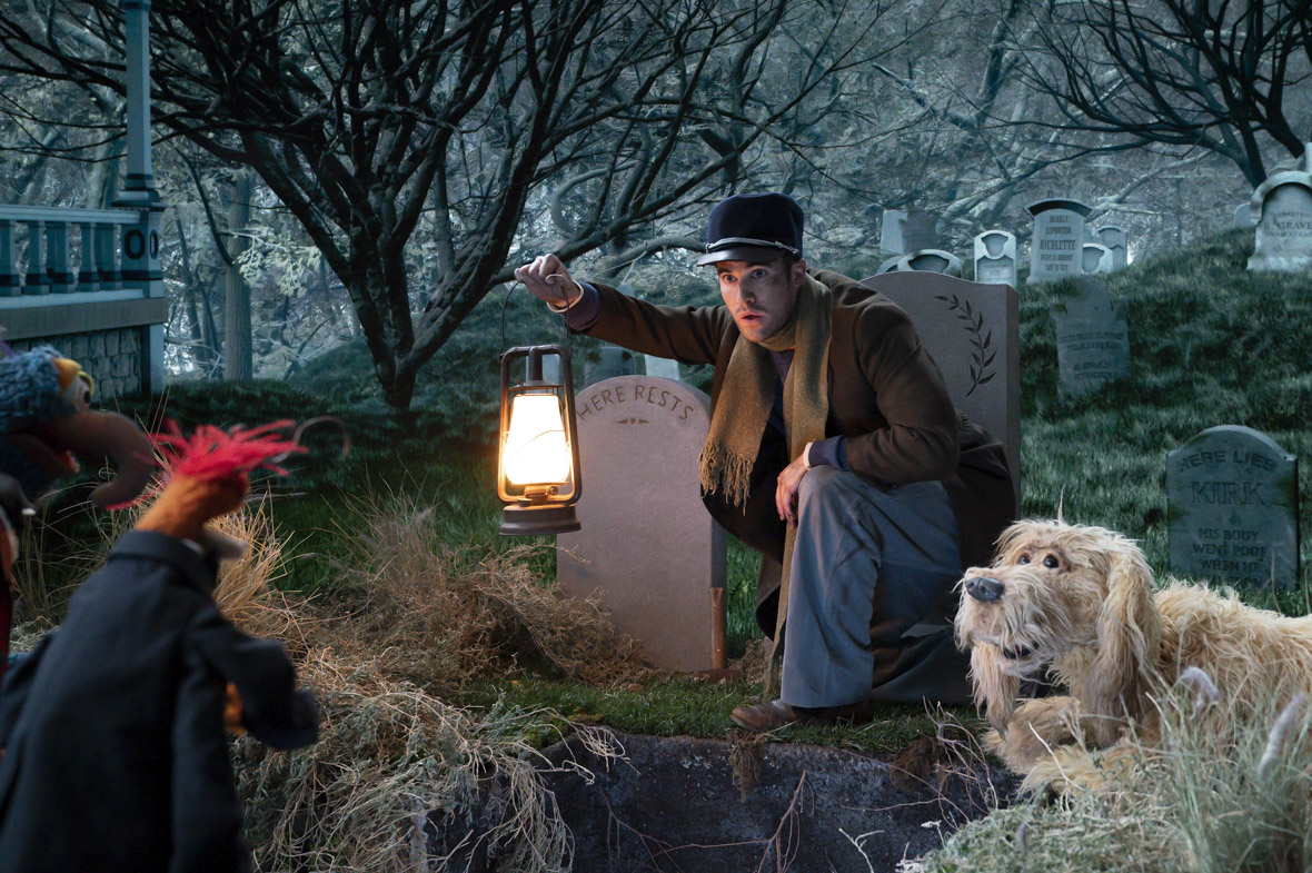 The Caretaker (Darren Criss), Gonzo, and Skeeter investigate an open grave in a scene from Muppets Haunted Mansion.