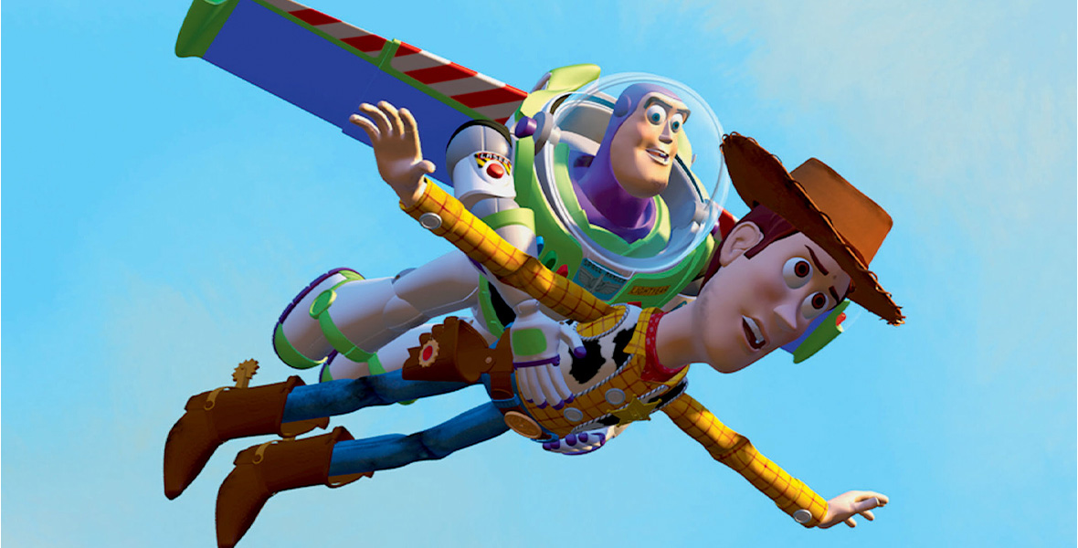 In a scene from Disney and Pixar’s animated film Toy Story, Buzz Lightyear, a spaceman action figure with wings, a laser, and a helmet holds Woody, a pull-string cowboy rag doll, as they fly through a bright blue sky. Buzz Lightyear wears an all-white space suit with green accents on the chest, gloves, and boots, and purple wings. Woody wears a brown cowboy hat, a red bandana tied around his neck, a cow print vest, a yellow button-down shirt with red stripes, blue denim pants, and brown cowboy boots with gold spurs on the heels. Woody also wears a large sheriff badge on the left side of his vest.