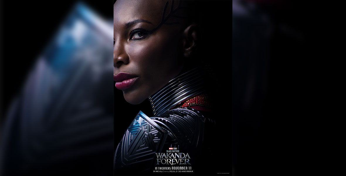Aneka (Michaela Coel) looks over her shoulder at the camera, shrouded in darkness except for her face and the shiny silver of her shoulder and collar.