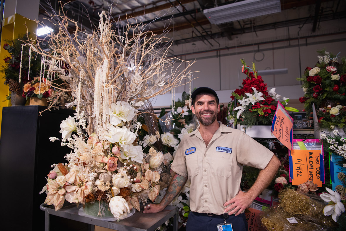 Cast member Brandon Griewank stands next to a floral arrangement he has designed and constructed in the Resort Enhancement warehouse in Anaheim, California.