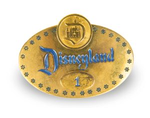 A photo depicts Disney Employee Badge Number 1, one of the historical artifacts that will be included in Disney100: The Exhibition. The badge has been photographed against a neutral white background.&nbsp;