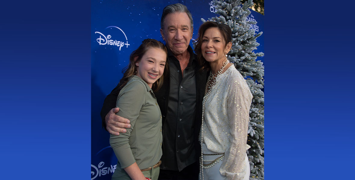 The Allen family—Elizabeth Allen-Dick, Tim Allen, and Jane Hajduk in front of a Christmas tree and a dark blue backdrop with Disney+ and The Santa Clauses branding.