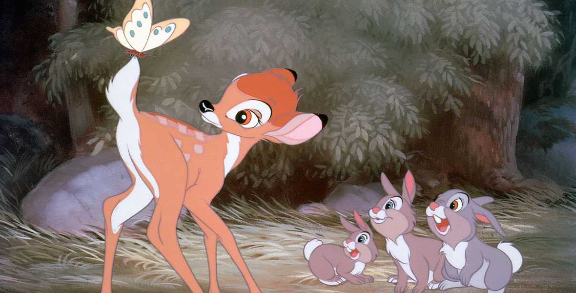 A still from the 1942 animated film Bambi; in the forest, Bambi the deer is on the left, and a butterfly is resting on his tail. To his right are three rabbits looking up at him with smiles on their faces.