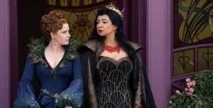 Giselle and Malvina, both wearing elaborate fairy tale-inspired gowns, glare at each other in front of a purple doorway.