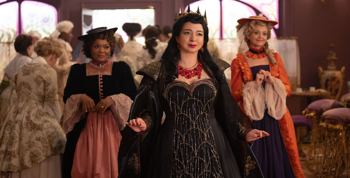 Rosaleen and Ruby flank Malvina as they all walk through a crowded room. Malvina is dressed like an evil queen, while Rosaleen and Ruby both wear simpler gowns and hats.