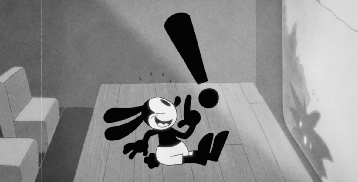 The black and white animated character Oswald the Lucky Rabbit sits on the stage of a movie theater. He points to a black exclamation point in the air above him.