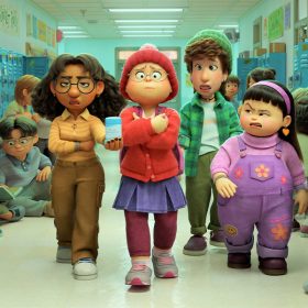 Mei-Mei and her friends walk down the school hallway in Turning Red. Mei is wearing a red sweater, a purple skirt, and purple leggings whole holding onto her books.