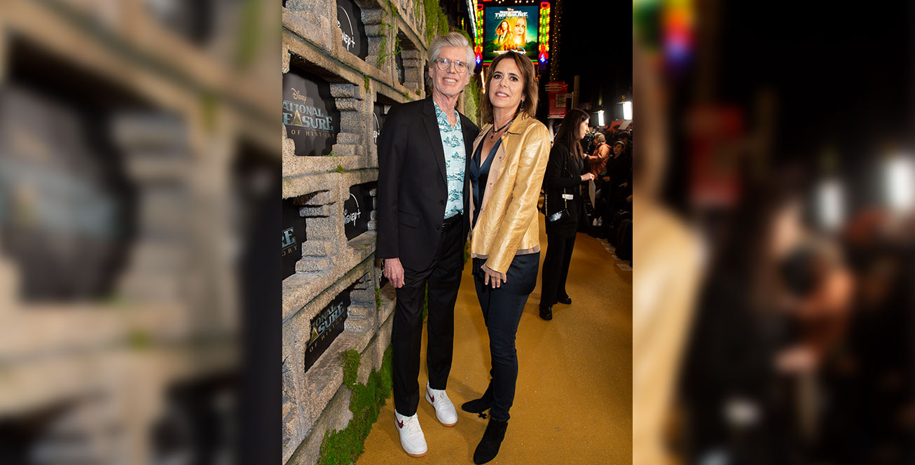 Cormac and Marianne Wibberly stand on the gold carpet at the world premiere of National Treasure: Edge of History. Behind them is the marquee for the El Capitan Theatre, featuring a poster of the series.