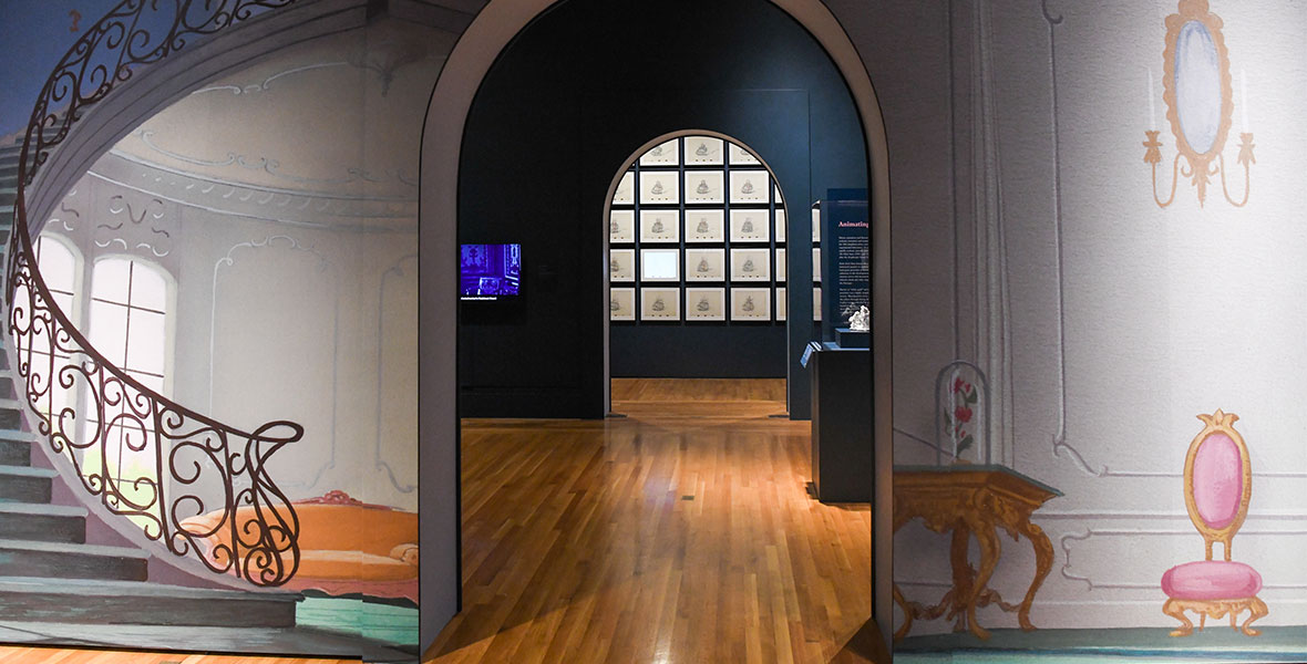 A view of the interior of the exhibition Inspiring Walt Disney: The Animation of French Decorative Arts leading into the first two galleries featuring original artwork by Disney artists as seen from the entryway.
