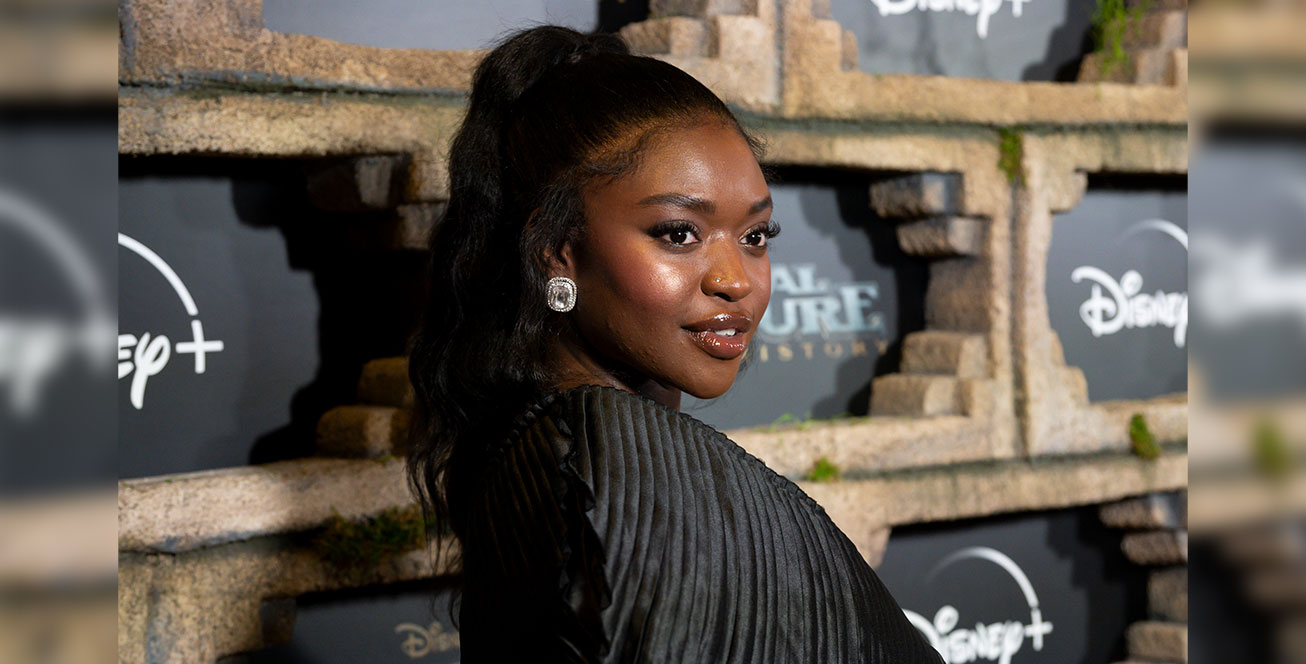 Zuri Reed looks over her shoulder to pose for a photo in front of the step and repeat at the National Treasure: Edge of History world premiere.