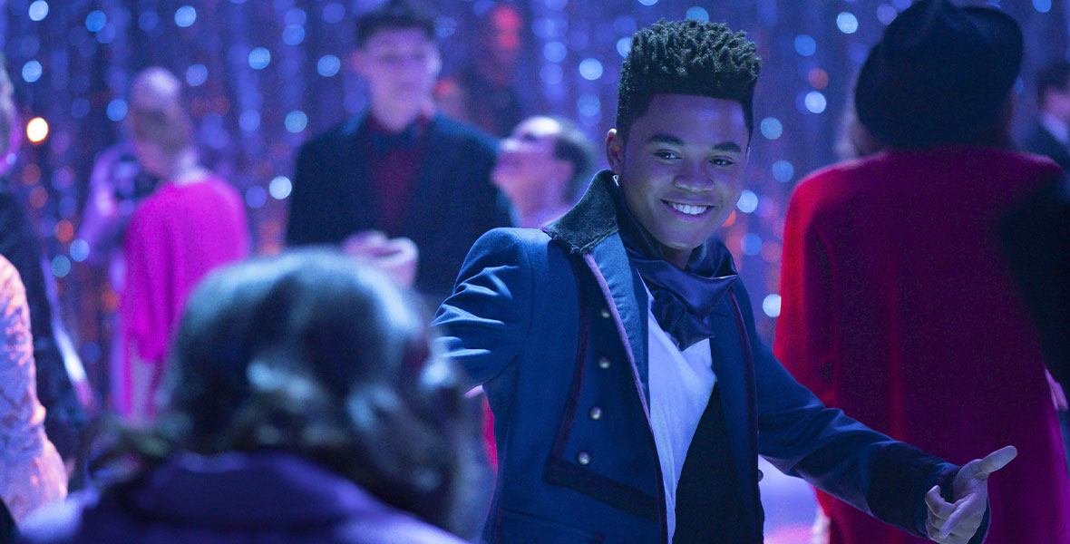 Chosen Jacobs wears a topcoat and smiles. He is at a school dance.