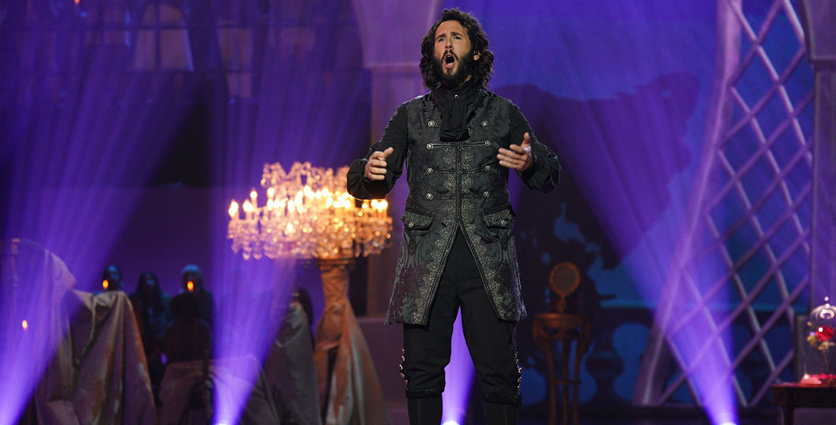 Josh Groban, wearing an all-black fairy tale look, stands center stage and sings his heart out.