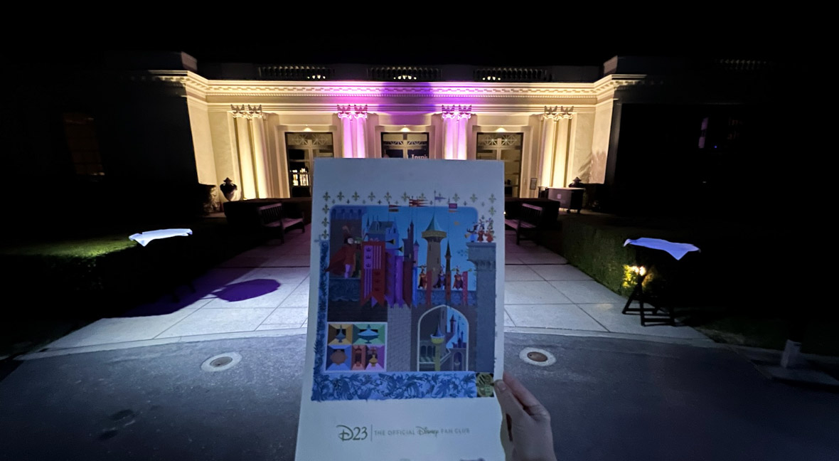 Event gift print pictured in front of The Huntington Museum lit in purple and yellow lights. The print features French artwork that inspired Sleeping Beauty.