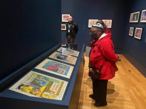 Guests looking at display case of storybook pages. The guest is wearing a red coat and black jeans.