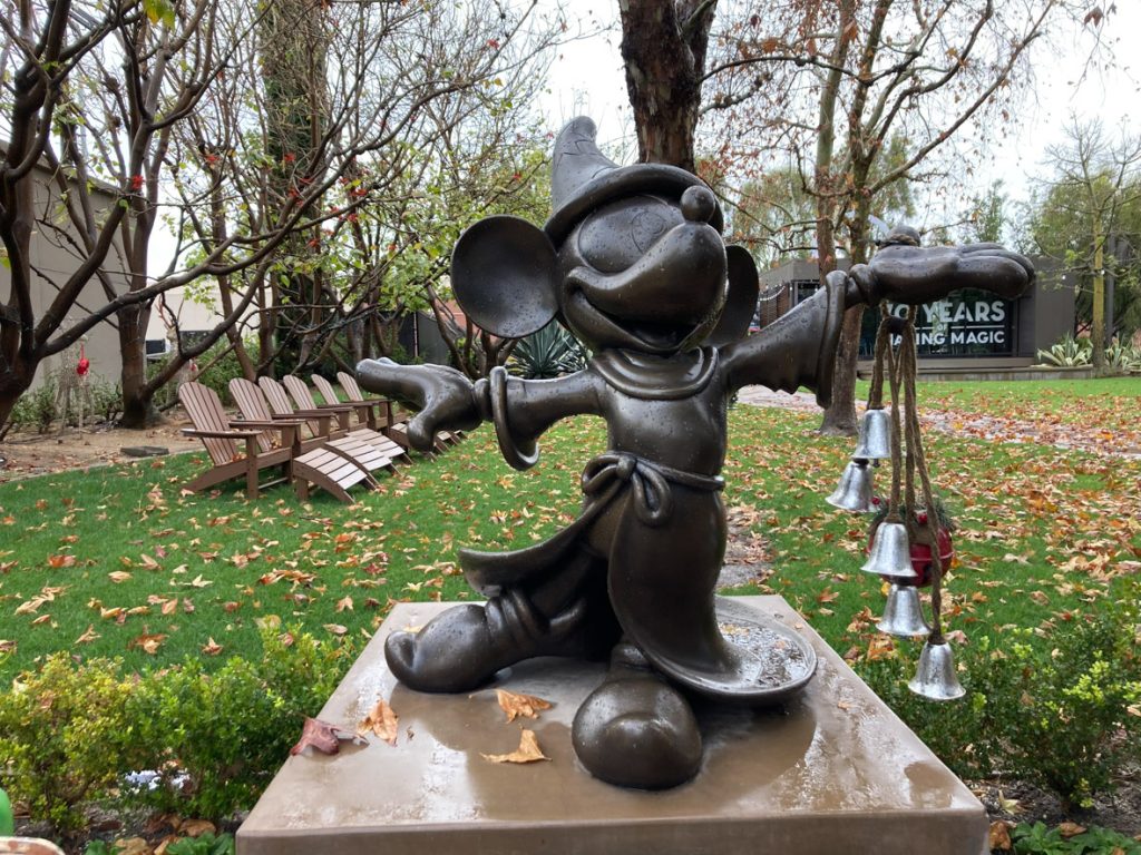 Bronze statue of Sorcerer Mickey with holiday bells hanging from his hand.