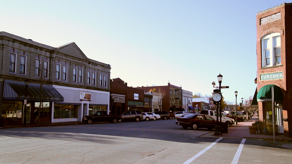 A street in Marceline, Missouri flanked by buildings and parked cars.