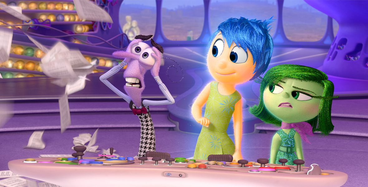 In a scene from Pixar’s Inside Out, characters Panic, Joy, and Disgust stand at a control panel and look at papers flying in the air.