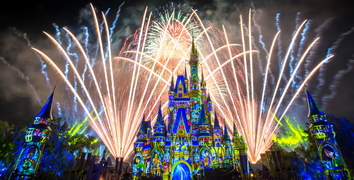 A finale shot from Happily Ever After at Magic Kingdom Park. Cinderella Castle is illuminated with bright projection-mapped images of Disney characters, including Mulan, Tarzan, Cinderella, Aladdin, Woody, Merida, and more. Fireworks illuminate the sky behind the castle.