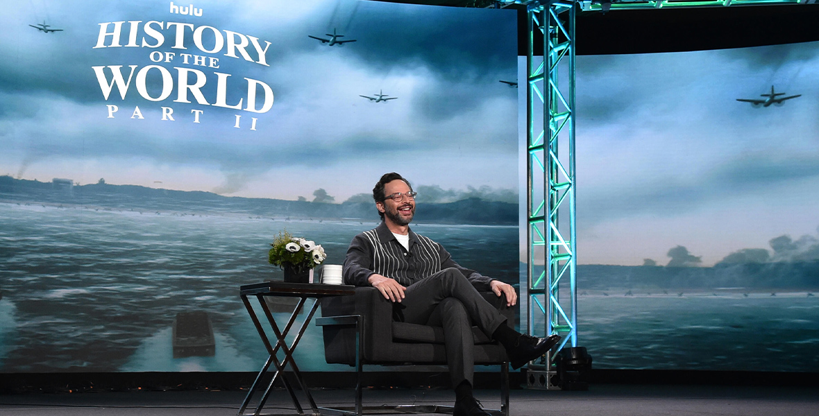 Actor Nick Kroll sits in a black leather chair onstage at the 2023 Winter Television Critics Association panel for History of the World, Part II.