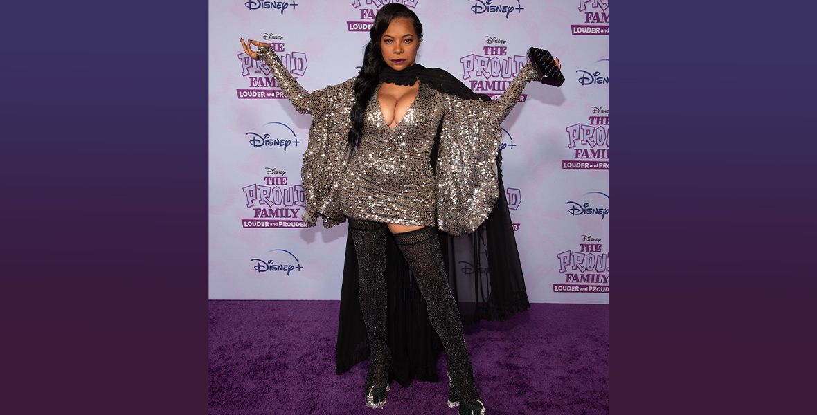 Karen Malina White strikes a dramatic pose in a sparkly, silver gown in front of a The Proud Family: Louder and Prouder step and repeat.