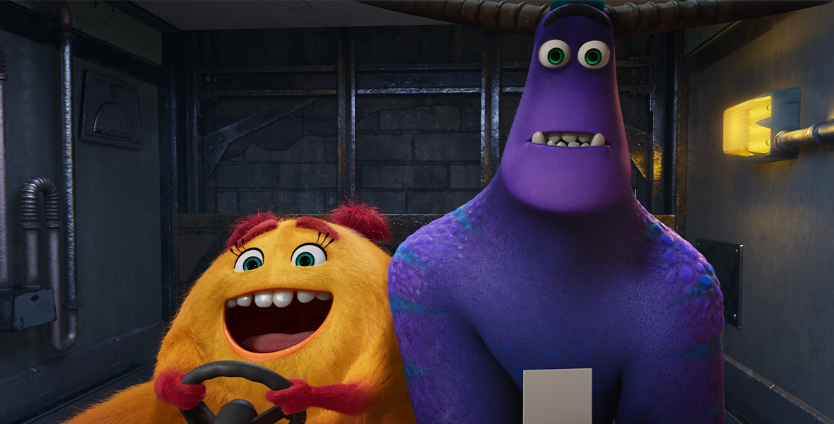 In a scene from Monsters at Work, an orange furry monster with red eyebrows, red pigtails, and red hands steers a motorized cart. A tall purple and blue scaly monster with two large horns sits on the cart and holds a piece of paper.