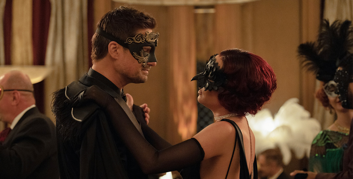 In a scene from an episode of The Watchful Eye, actors Warren Christie as Matthew and Mariel Molino as Elena dance as they wear masquerade masks and formal attire.