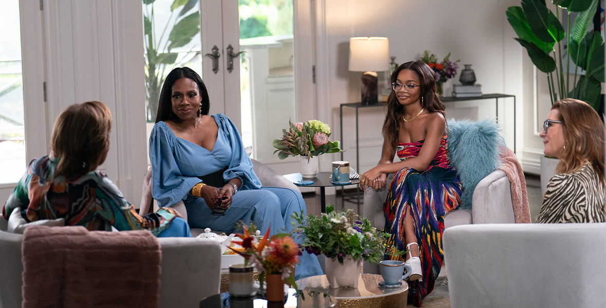 In a scene from Turning the Tables with Robin Roberts, Robin Roberts sits in a gray chair with her back to the camera and speaks to a group of women. To her left is Sheryl Lee Ralph; to Ralph’s left is Marsai Martin; and to Martin’s left is Brooke Shields.