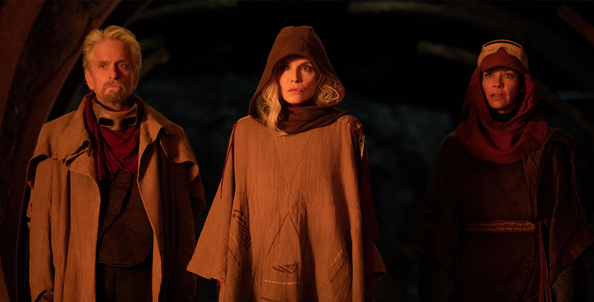 Hank Pym, played by Michael Douglas, Janet van Dyne, played by Michelle Pfeiffer, and Hope van Dyne, played by Evangeline Lilly, are wearing earth-toned jackets, tunics, headscarves, and goggles. They are surrounded by blackness.