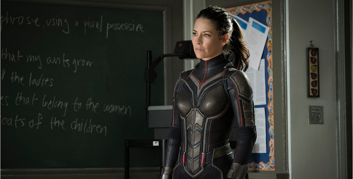 In a scene from Ant-Man and The Wasp, actor Evangeline Lilly as Hope Van Dyne/The Wasp stands in a school classroom and wears a black jumpsuit.